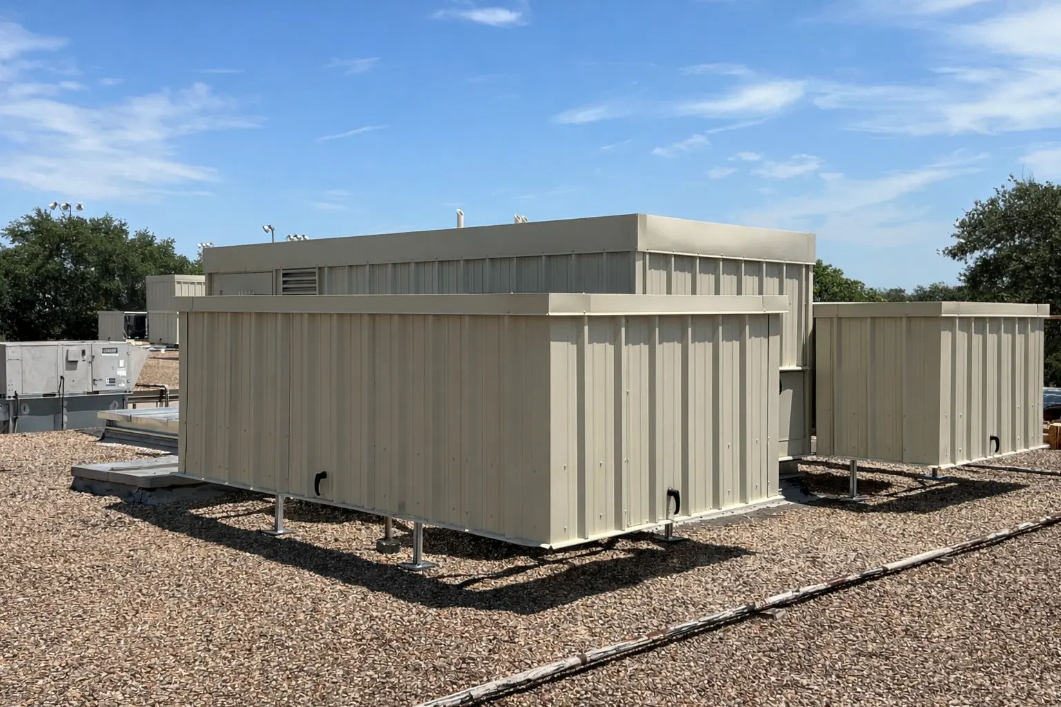 Tan steel equipment screens enclosing rooftop mechanical units on a ballasted roof