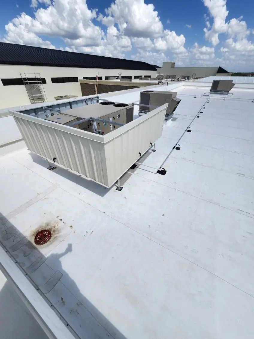 Non-penetrating rooftop equipment screen set on a white membrane roof